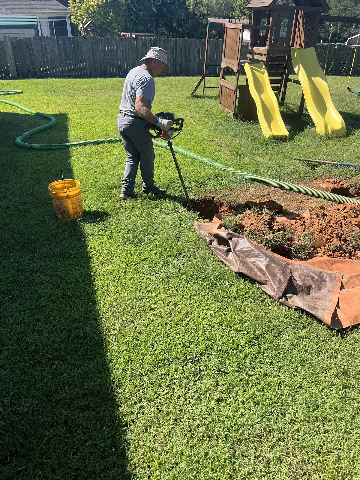 Aardvark pumping a septic tank in a suburban backyard near a play set