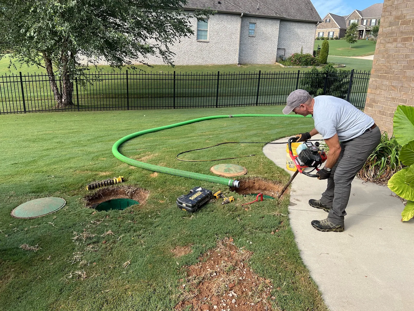 Aardvark technician pumping a home septic tank with the green suction hose